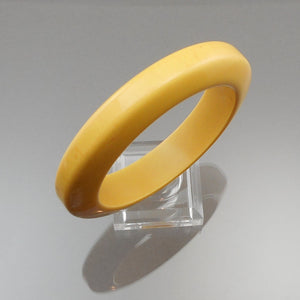 A vintage authentic bakelite plastic bangle bracelet. Opaque creamed corn yellow with streaks of brown. Simichrome tested.  Approximately 5/8" x 3 3/8" diameter; inside opening diameter is 2 1/2"  47.1 grams  Vintage pre-owned original condition with expected scratches.