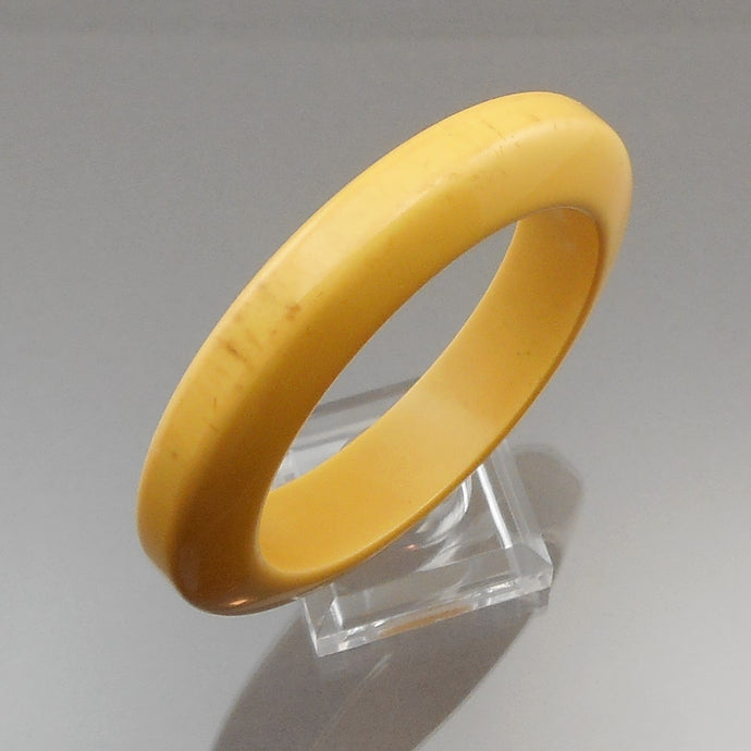 A vintage authentic bakelite plastic bangle bracelet. Opaque creamed corn yellow with streaks of brown. Simichrome tested.  Approximately 5/8