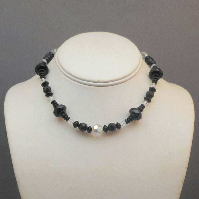 An Art Deco Era necklace of French jet (black glass) and aurora borealis beads. Choker length with opaque and iridescent round, bicone and faceted disc beads.  Beads vary from approx 5 - 12mm, necklace length is 14 1/2