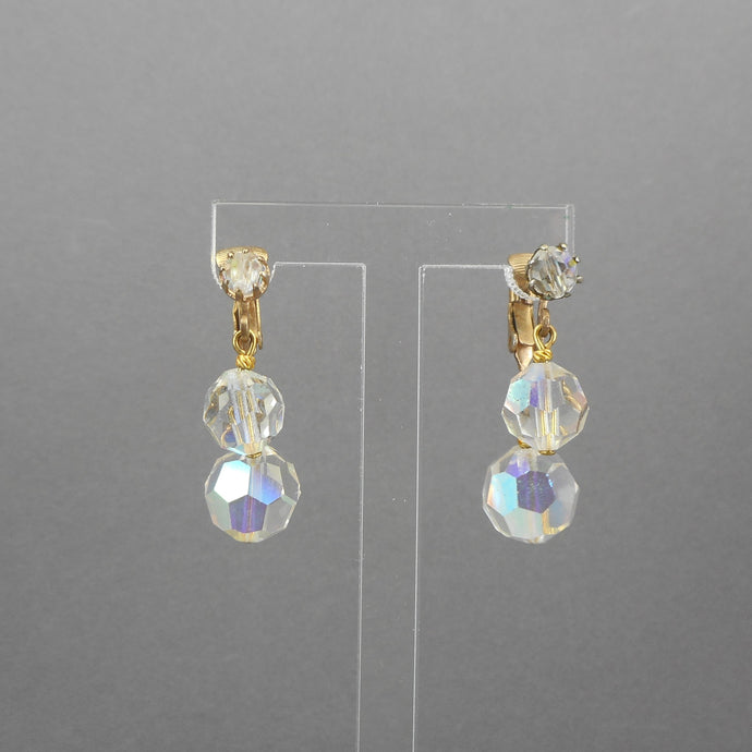 A circa 1950 pair of clip on dangle earrings with clear aurora borealis (AB) clear glass beads and gold tone settings.  Each approximately 1/2