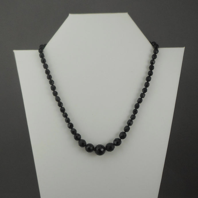 A vintage single strand necklace of French jet (black glass) beads. Collar length, adjustable, with graduated sized faceted round beads.  Approximately 17